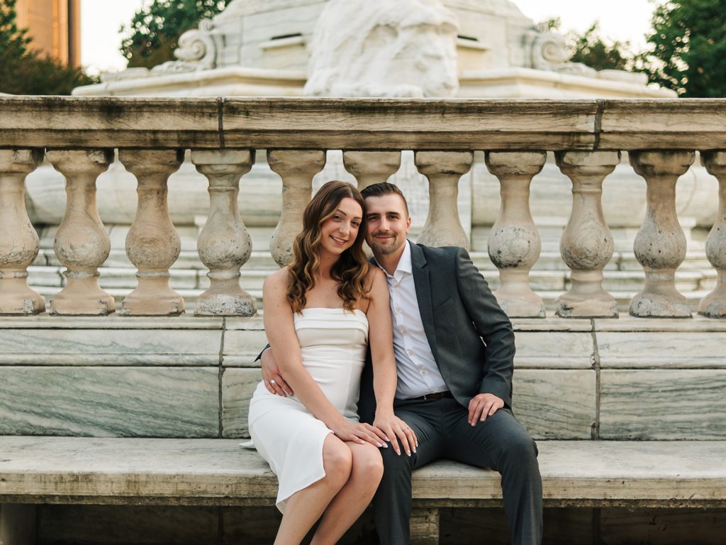 Couple in earth tone outfits hand in hand along Buffalo city hall/Niagara Square during couples session
