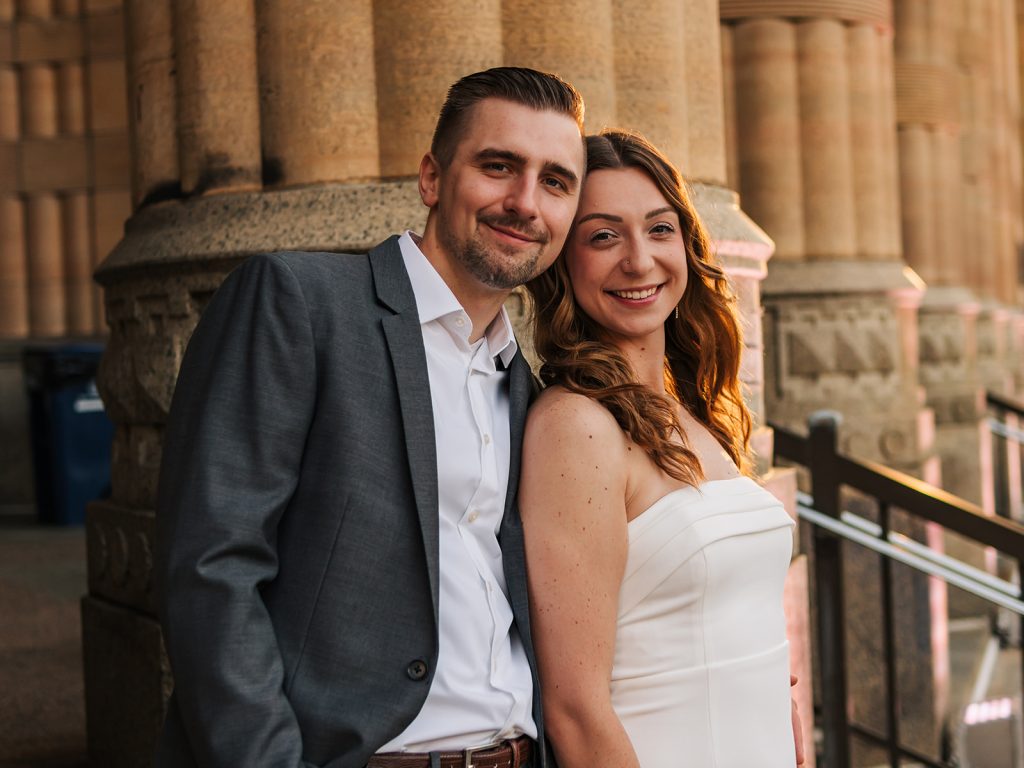 Happy couple together during golden hour couples session at Buffalo city hall with warm lighting