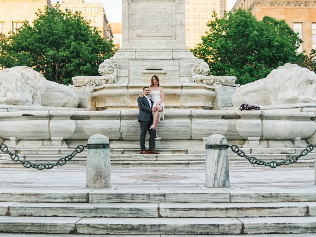 Couple in earth tone outfits hand in hand along Buffalo city hall/Niagara Square during couples session